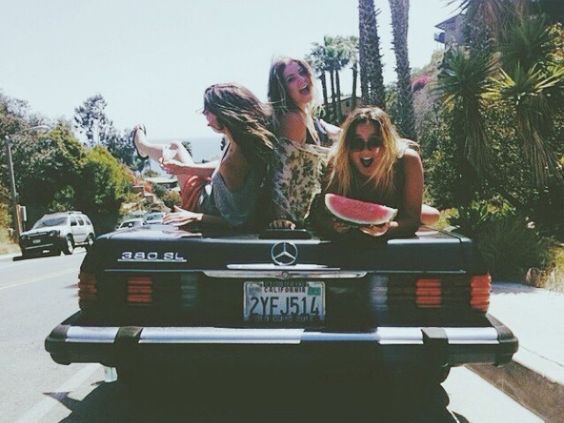 Girls sitting on the back of a car having fun