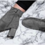 Grey ankle boots and black jeans on marble surface