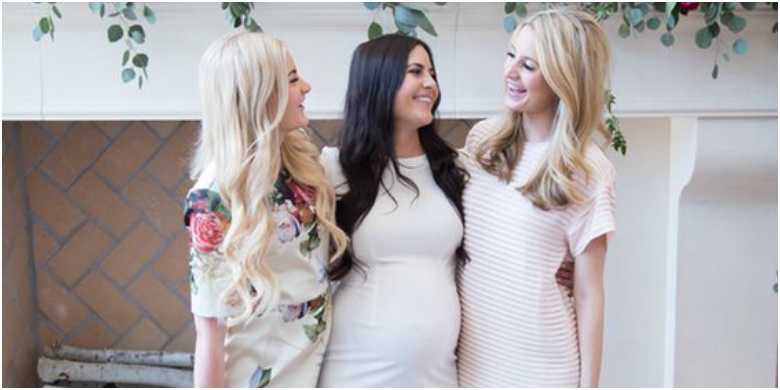 Three women in neutral coloured dresses in baby shower setting