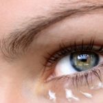Woman with eye cream dabbed beneath her eye