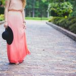 Woman wearing ombre pink maxi dress styled with black hat and sandals