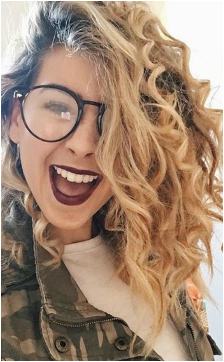 Zoella with corkscrew curls, glasses and camo jacket
