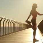woman in running gear stretching on pier