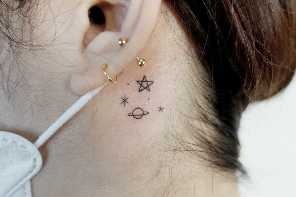 Tiny shooting star tattoo located on the ear