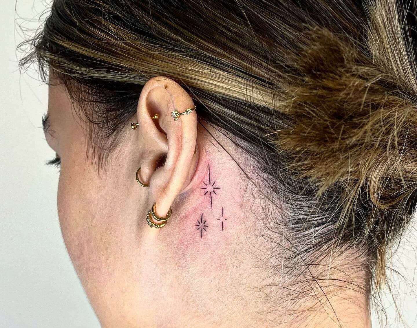 Minimalist letter F tattoo behind the ear