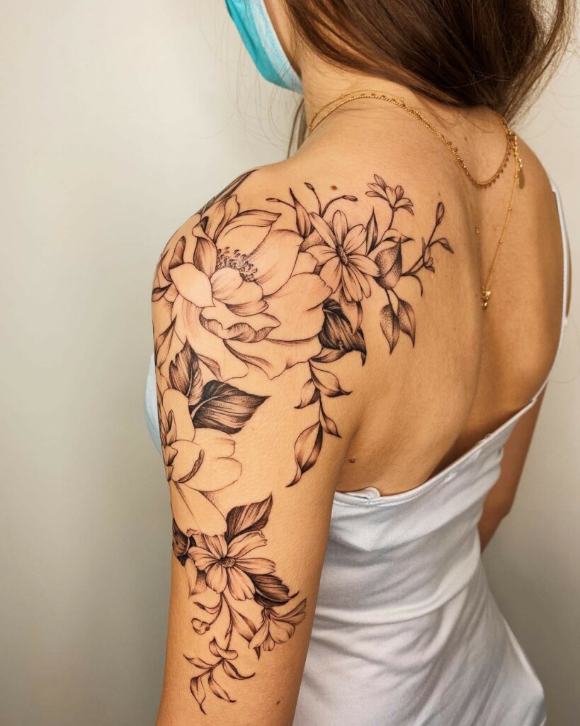 Flower head woman tattoo located on the shoulder blade.
