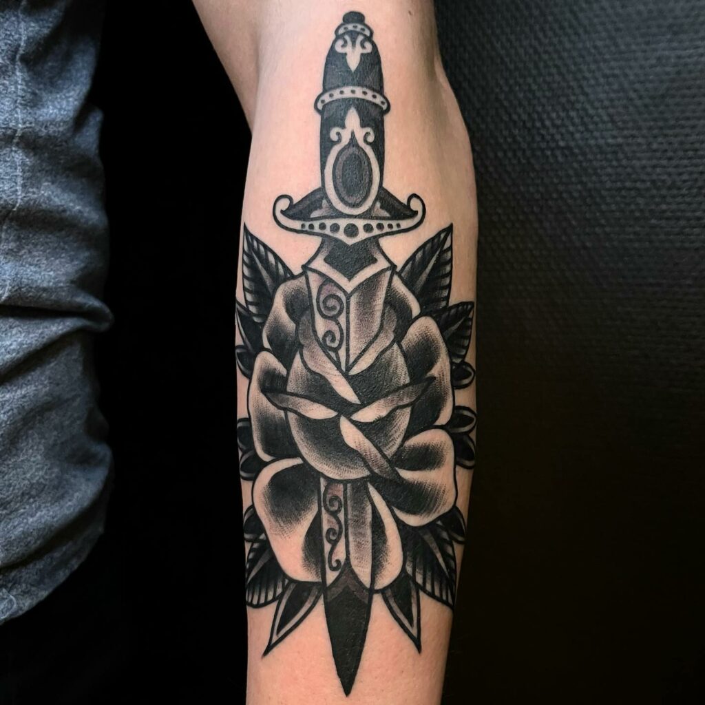 Black and grey dagger tattoo located on the tricep