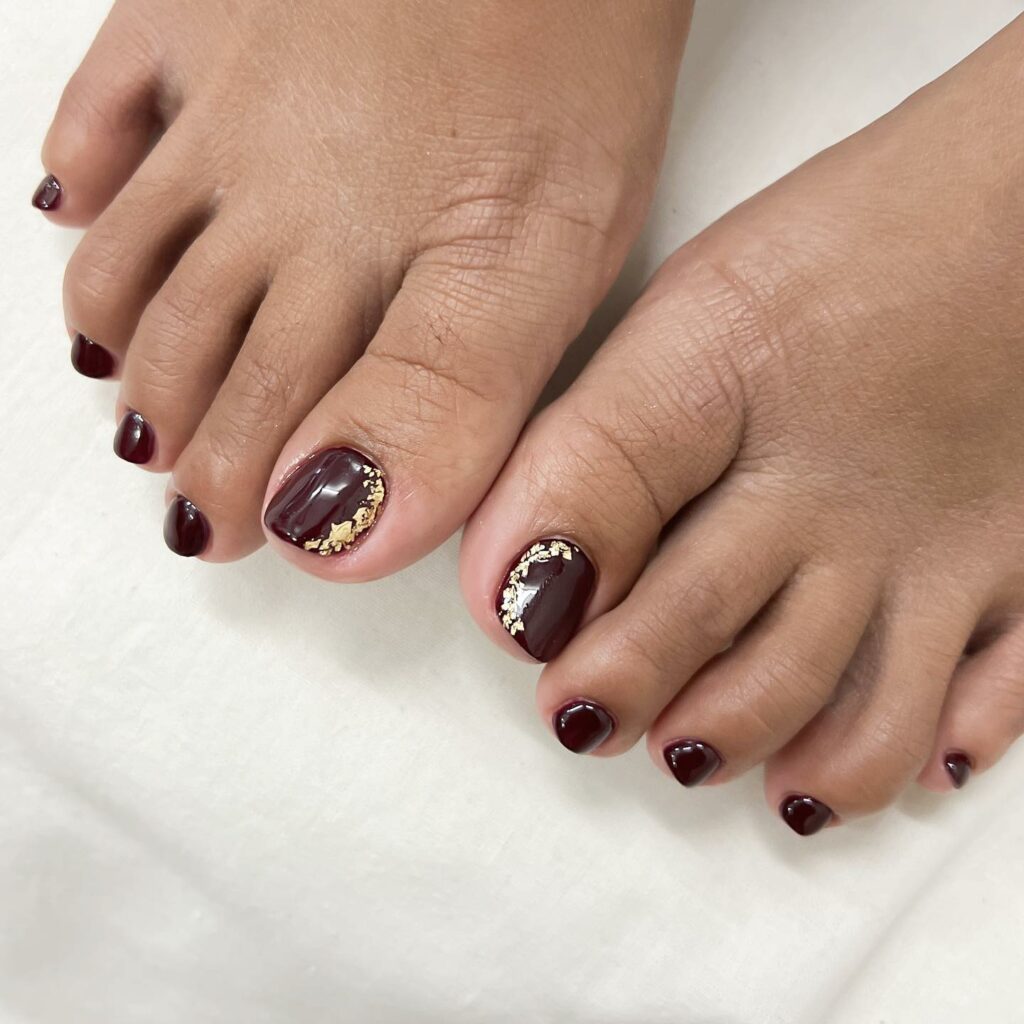 Dark Burgundy Pedicure With Gold Flakes