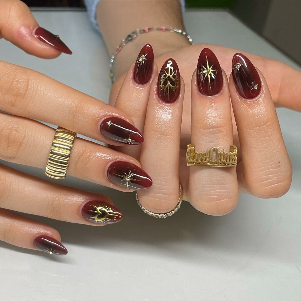 Burgundy Nails Adorned with Gold Hearts and Stars