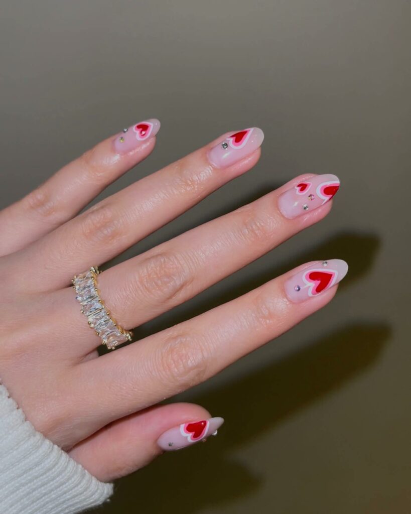 Red Hearts On Nude Almond Nails With Rhinestones