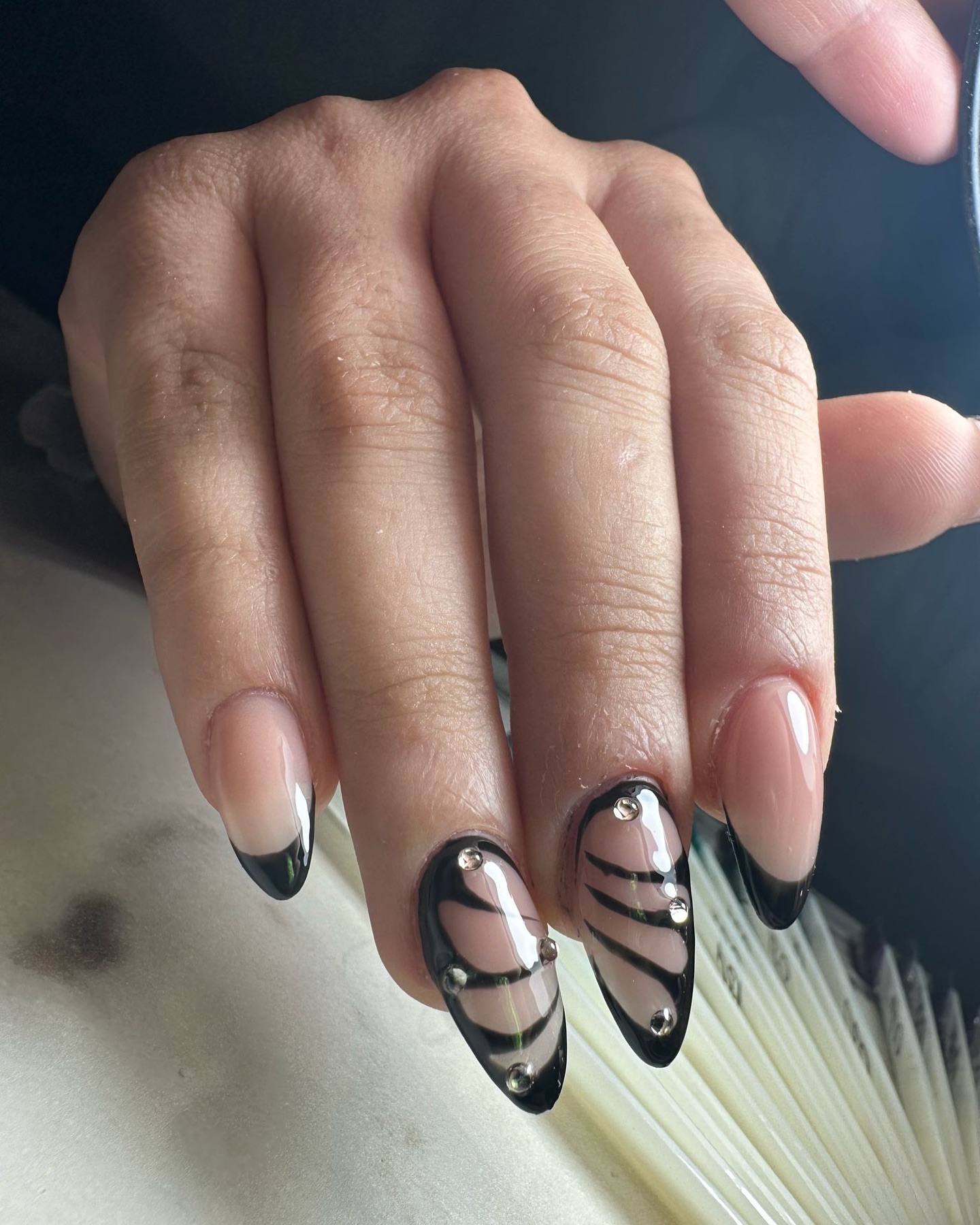 Chic Black and Nude Almond Nails with Stripes and Gems